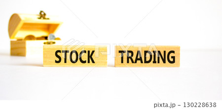 Stock trading symbol. Concept words Stock trading on beautiful wooden blocks. Beautiful white table white background. Wooden beautiful chest with coins. Business stock trading concept. Copy space. 130228638