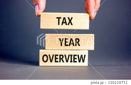 Tax year overview symbol. Concept words Tax year overview on beautiful wooden blocks. Beautiful grey background. Businessman hand. Business tax year overview concept. Copy space. 130228751