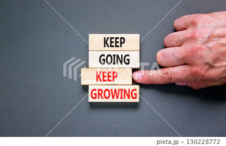 Keep going and growing symbol. Concept words phrase Keep going keep growing on beautiful wooden blocks. Beautiful grey background. Businessman's hand. Business Keep going growing concept. Copy space. 130228772