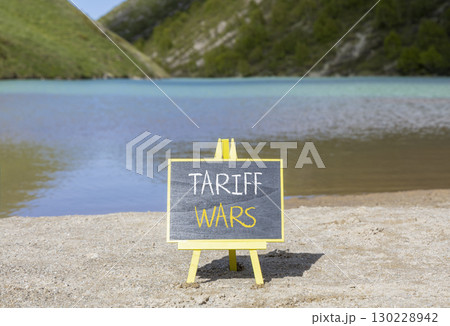 Trade tariff wars symbol. Concept word Tariff wars on beautiful black blackboard. Beautiful mountain lake sand beach background. Black blackboard. Business trade tariff wars concept. Copy space. 130228942