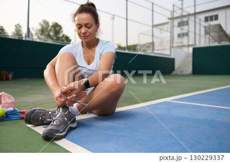 Woman Preparing for Tennis Practice on Outdoor Court 130229337