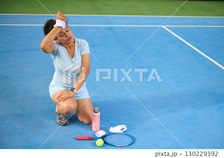 Tennis Player Resting on Court with Gear and Water Bottle Tennis Player Resting on Court with Gear and Water Bottle 130229392