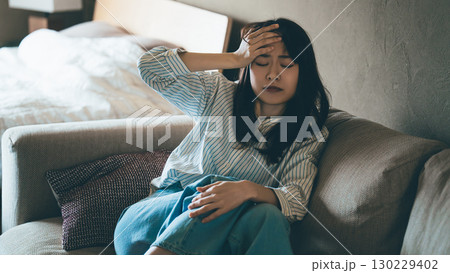 頭を押さえて悩む女性 頭を押さえて悩む女性 130229402