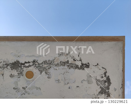 Corner of a weathered white building against a clear blue sky background view 130229621