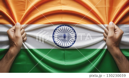 Hands pulling apart an indian flag revealing the chakra in the center 130230039