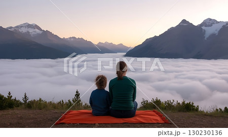 Mother and child sit on blanket overlooking a valley filled with clouds Mother and child sit on blanket overlooking a valley filled with clouds 130230136