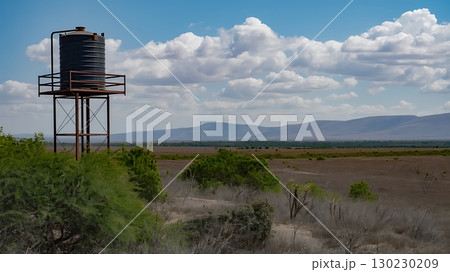 Water tower stands tall against a backdrop of clouds and distant mountains 130230209