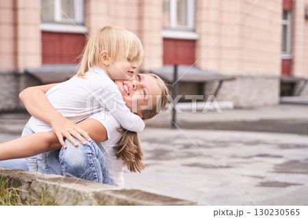 Caucasian female child hugging young adult woman outdoors on a sunny day 130230565