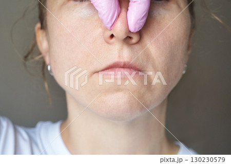 Female caucasian adult receiving nose examination with pink medical gloves Female caucasian adult receiving nose examination with pink medical gloves 130230579