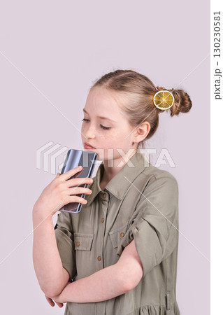 Young caucasian female child with lemon hair accessory holding smartphone 130230581