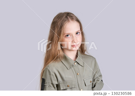 Caucasian child with long hair wearing green shirt and neutral expression 130230586