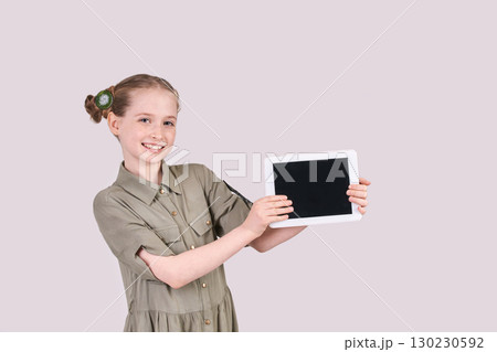 Caucasian young female child showing blank tablet screen with green dress Caucasian young female child showing blank tablet screen with green dress 130230592