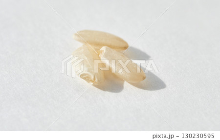 Macro shot of three uncooked white rice grains on light background with minimal 130230595
