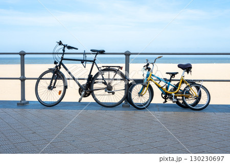 Adult and kids vintage bicycles on the street near the sea beach. Blue sea, yellow sand and summer sky. Bike for sport or travel. Adult and kids vintage bicycles on the street near the sea beach. Blue sea, yellow sand and summer sky. Bike for sport or travel. 130230697