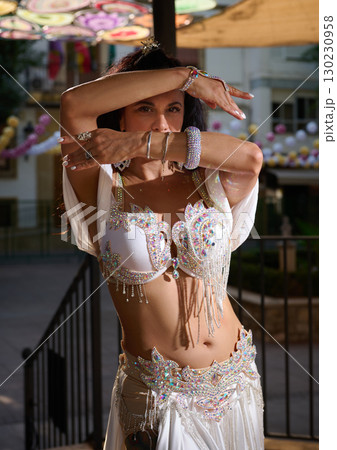 Elegant Woman Performing Belly Dance in White Costume Outdoors 130230958