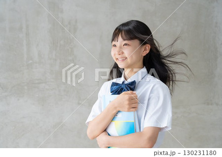 髪をなびかせて教材を抱える笑顔の女子学生 髪をなびかせて教材を抱える笑顔の女子学生 130231180