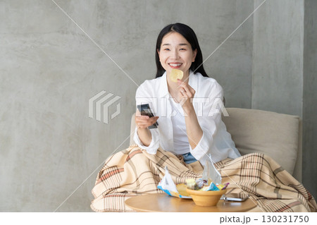 ソファでテレビを楽しむ大人の女性 130231750