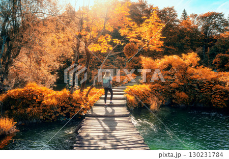 Woman with backpack walking on wooden path. Waterfalls in autumn 130231784