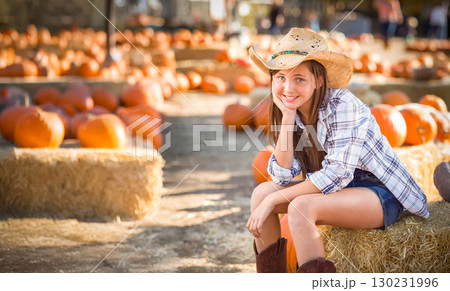 Pretty Girl Wearing Cowboy Hat Enjoying The Pumpkin Patch on a Sunny Fall Day. Pretty Girl Wearing Cowboy Hat Enjoying The Pumpkin Patch on a Sunny Fall Day. 130231996