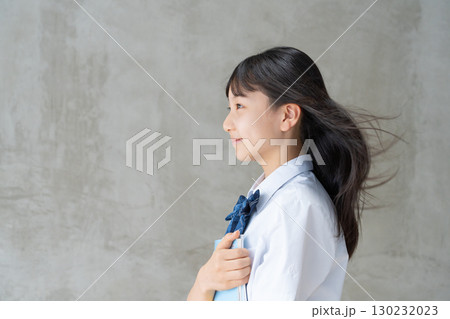 髪を風になびかせ教材を持つ女子学生の横顔 130232023