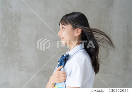 髪を風になびかせ教材を持つ女子学生の横顔 130232025