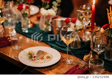 Gourmet fish fillet served with creamy sauce and microgreens on elegant dinner table 130232996