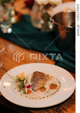 Elegant gourmet fish dish on festive table with romantic candlelight ambiance 130233003