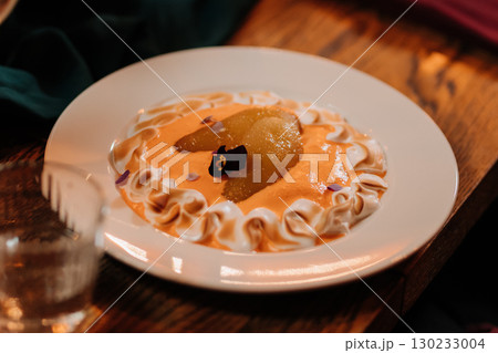 Elegant pear dessert with whipped cream and edible flowers on a rustic wooden table 130233004