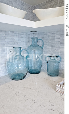 Three elegant blue glass vases of varying sizes displayed on a marble countertop, enhancing modern kitchen decor with stylish accents 130233145
