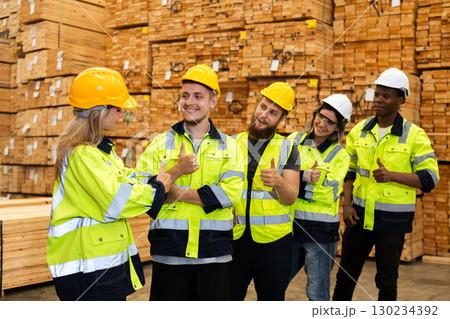 Group of multicultural industrial workers, celebrating teamwork success in a lumber warehouse while wearing safety gear and giving thumbs up. Group of multicultural industrial workers, celebrating teamwork success in a lumber warehouse while wearing safety gear and giving thumbs up. 130234392