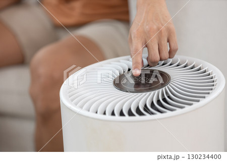 Close up of hand pressing power button air purifier for clean air in house for good health. Close up of hand pressing power button air purifier for clean air in house for good health. 130234400