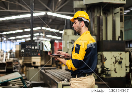 Engineer or factory worker using laptop for machine monitoring in industrial environment, representing manufacturing, digital factory, and industrial automation. 130234567