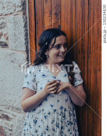 Smiling Young Woman Leaning on Wooden Door 130234830
