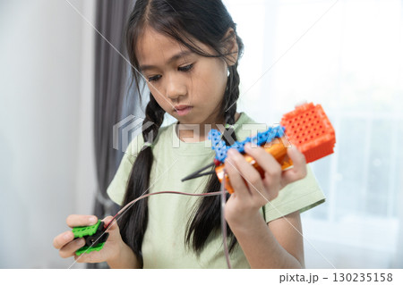 Focused asian girl assembling colorful STEM robotics project, connecting wires and parts to enhance creativity, engineering skills, and problem-solving through hands-on learning. Focused asian girl assembling colorful STEM robotics project, connecting wires and parts to enhance creativity, engineering skills, and problem-solving through hands-on learning. 130235158