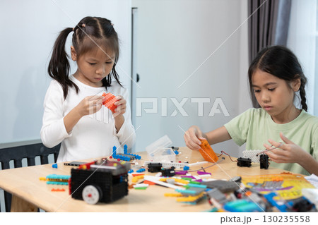Two young girls focus on assembling colorful robotics kits in a STEM class, enhancing creativity, problem-solving, and engineering skills through hands-on learning and teamwork. Two young girls focus on assembling colorful robotics kits in a STEM class, enhancing creativity, problem-solving, and engineering skills through hands-on learning and teamwork. 130235558