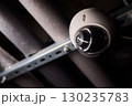 Surveillance Camera Placed in an Industrial Setting Surrounded by Various Pipes and Equipment 130235783