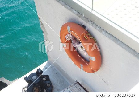 Lifebuoy hanging beside water in bright sunlight 130237617