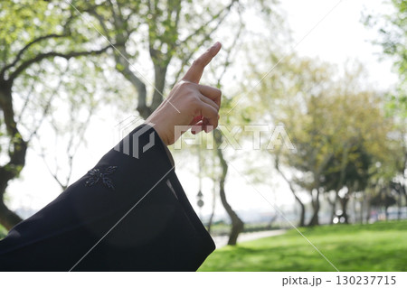Hand pointing towards the sky in a green park setting 130237715