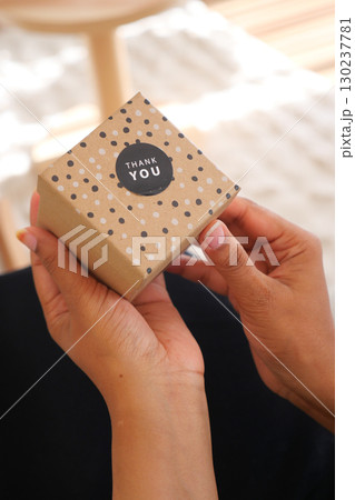 Gift box being opened with thank you note on a sunny day 130237781