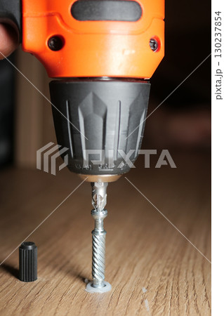 Using a drill to fasten a screw in wood Using a drill to fasten a screw in wood 130237854