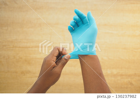 Person putting on blue medical gloves in a clean setting 130237982