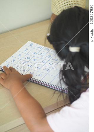Child practicing numbers at a home learning table 130237986