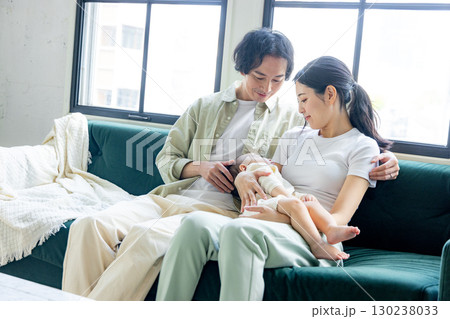 赤ちゃんを抱く若い夫婦 130238033