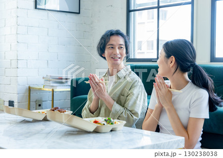 デリバリーでお弁当を注文して食べる男女 130238038