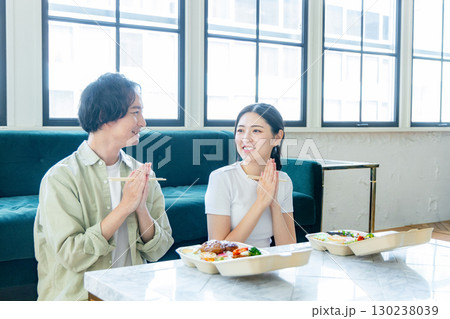 デリバリーでお弁当を注文して食べる男女 130238039