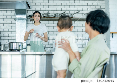 キッチンで料理をするママと子供の面倒を見るパパ キッチンで料理をするママと子供の面倒を見るパパ 130238043