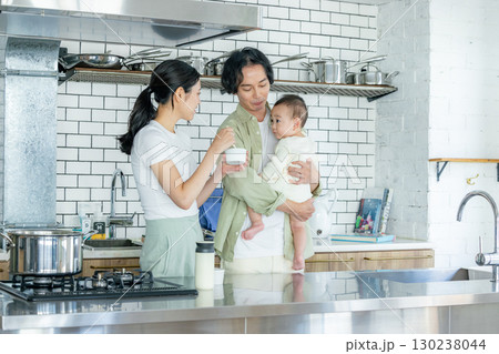 キッチンで料理をするママと子供の面倒を見るパパ 130238044