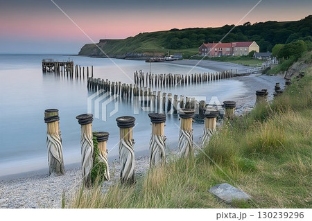 Tranquil Coastal Scene with Weathered Pier Supports at Dusk 130239296