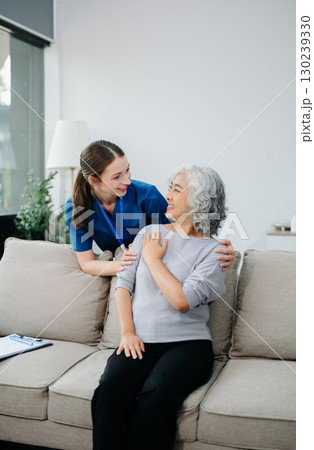Young nurse helping elderly woman walk in the room, holding his hand, supporting. Treatment and rehabilitation after injury Young nurse helping elderly woman walk in the room, holding his hand, supporting. Treatment and rehabilitation after injury 130239330