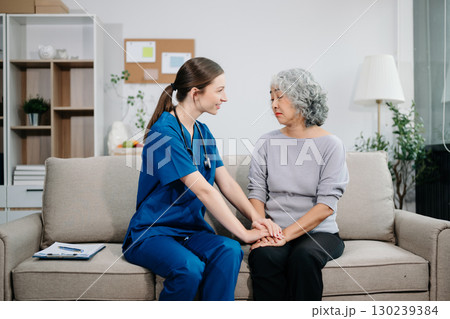 Young nurse helping elderly woman walk in the room, holding his hand, supporting. Treatment and rehabilitation after injury 130239384